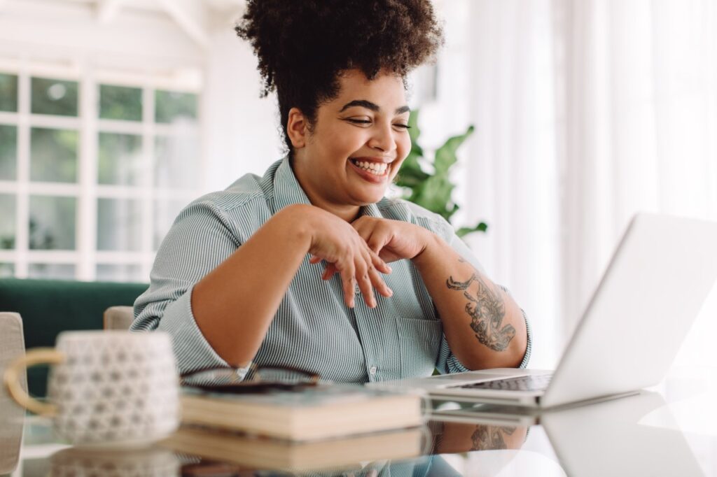 woman smiling while looking at her laptop