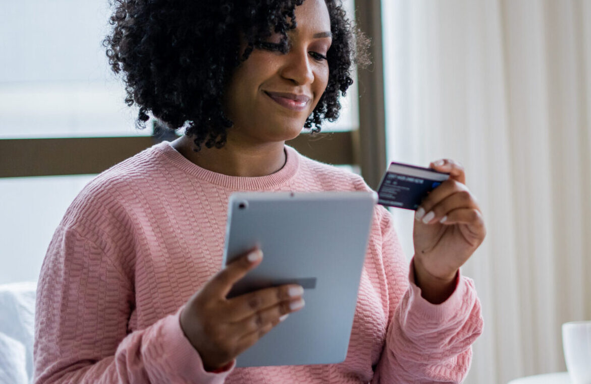 Woman holding a credit card and using a tablet to look at a chargeback