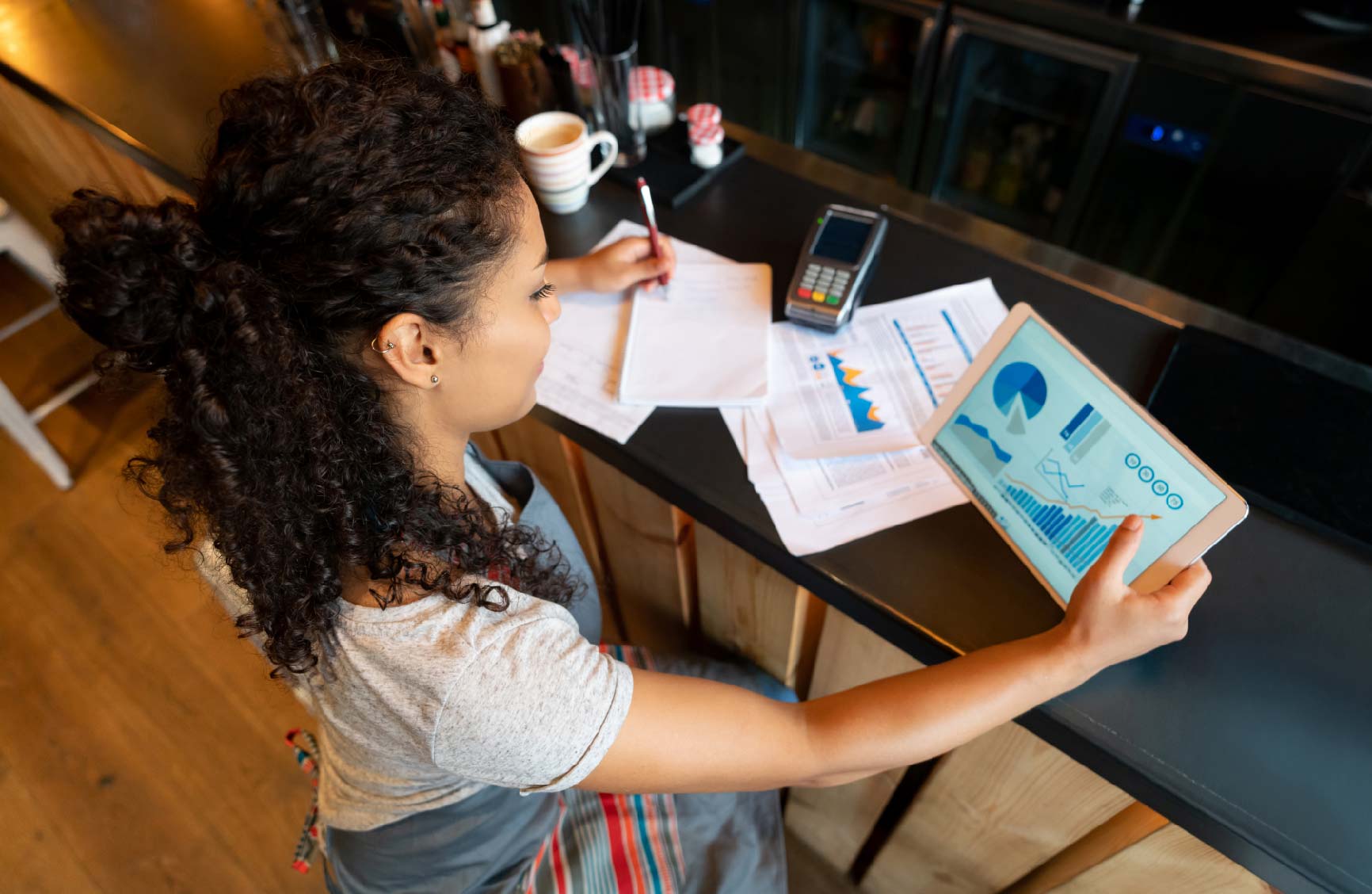 Woman reviewing chargebacks on a tablet with credit card merchant statements on a table