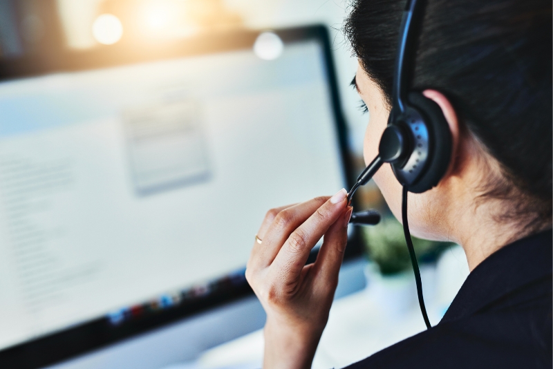Customer service representative wearing a headset and looking at a computer screen
