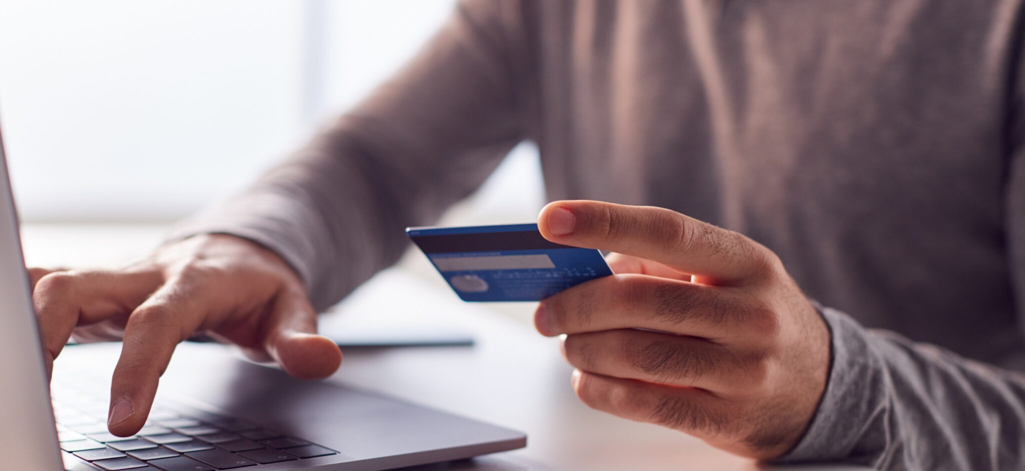 Person holding credit card and typing on a computer