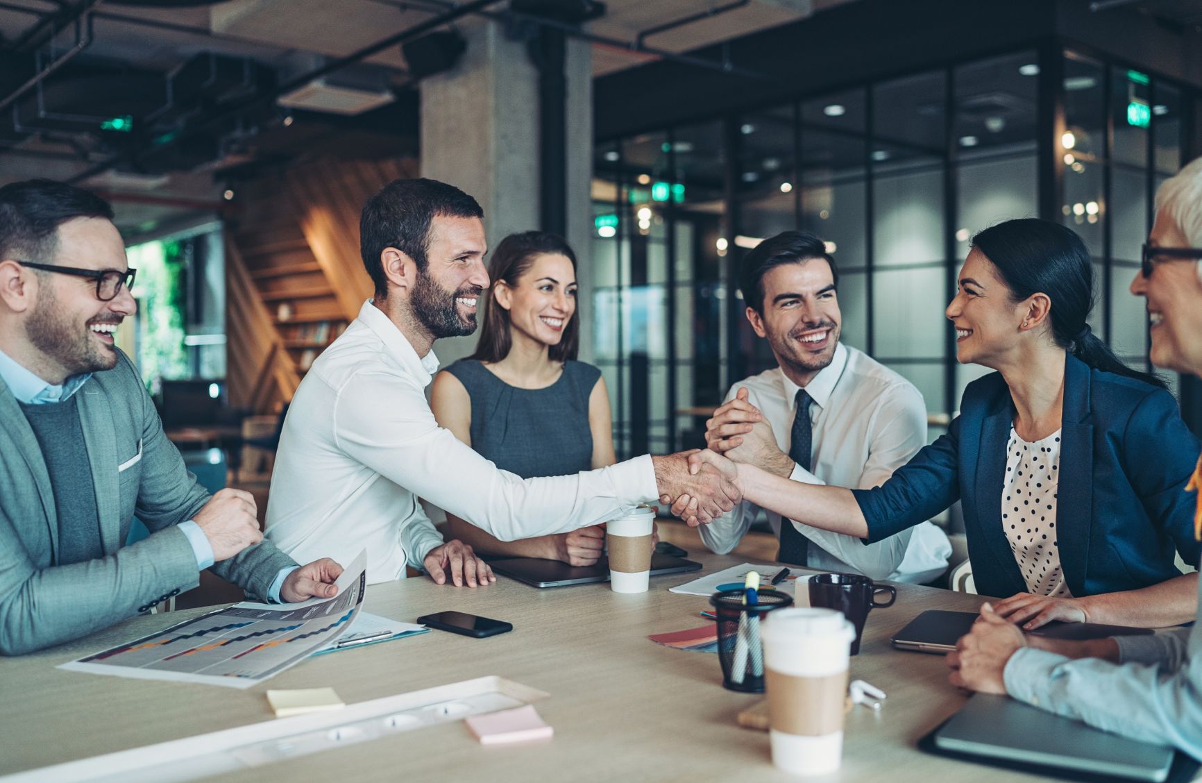 People at a conference table shaking hands