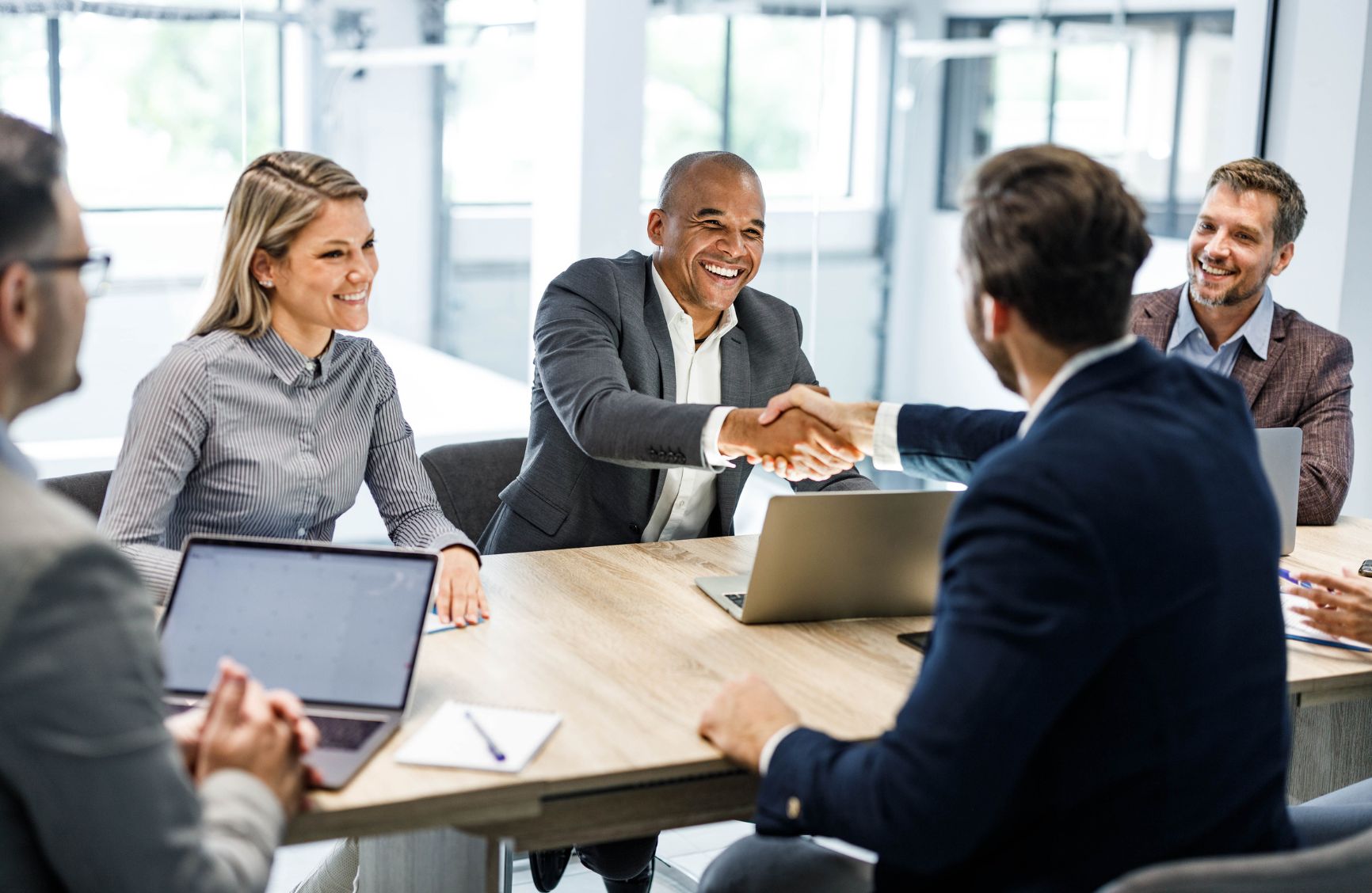 Man shaking someone's hand across a conference table.